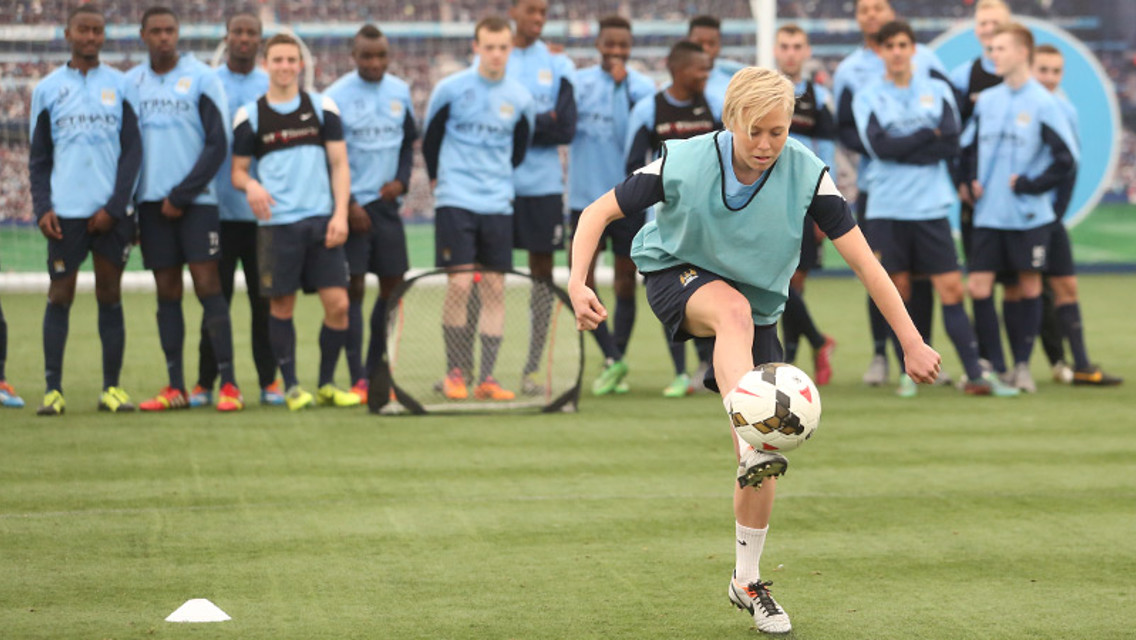 Betsy Hassett does keepy-uppys watched on by the u18 squad