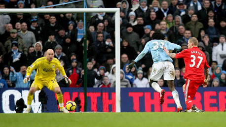 Adebayor is pushed by Skrtel as he takes a shot on goal