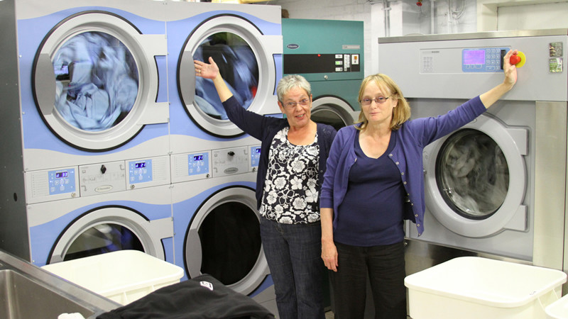 Anne and Janet with the shiny new washers and dryers cuts the cleaning tie down by half