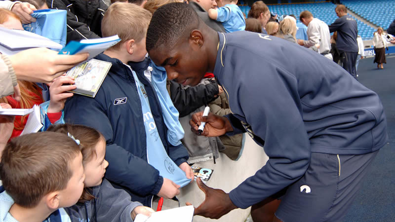 A young Micah at an open training session signing autographs
