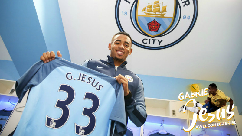 Gabriel Jesus holds up his City shirt in the dressing room