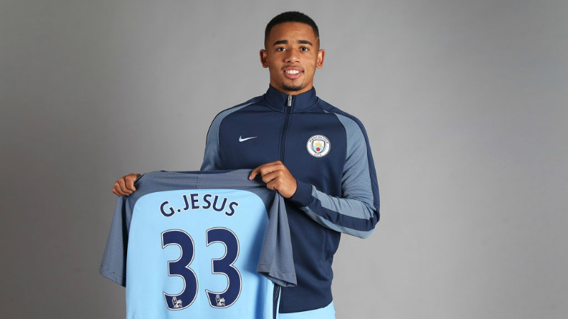 Gabriel Jesus holds up his new shirt, bearing the number 33