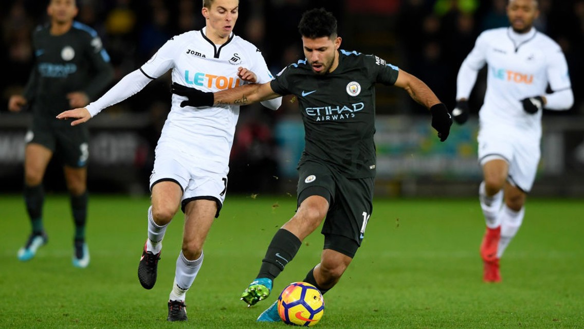 ON THE BALL: Sergio Agüero holds off Swansea's Tom Carroll in the middle of the park.