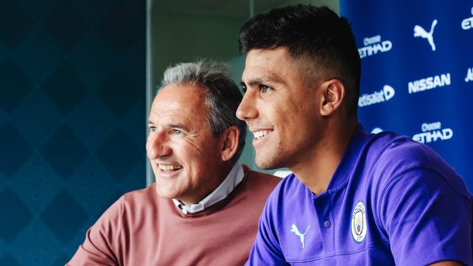 ALL SMILES : Rodri can't contain his happiness as he puts pen to paper and signs his City contract alongside Txiki Begiristain