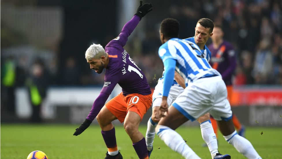 AT ARMS LENGTH : Sergio Aguero looks to shield the ball from the Huddersfield defence