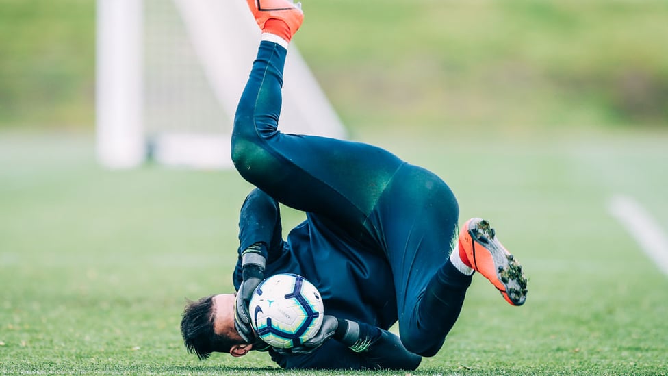 SAFE HANDS : Ederson gets down low