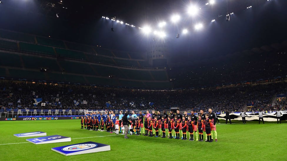 ALL LIT UP : The players line up at the San Siro ahead of kick-off