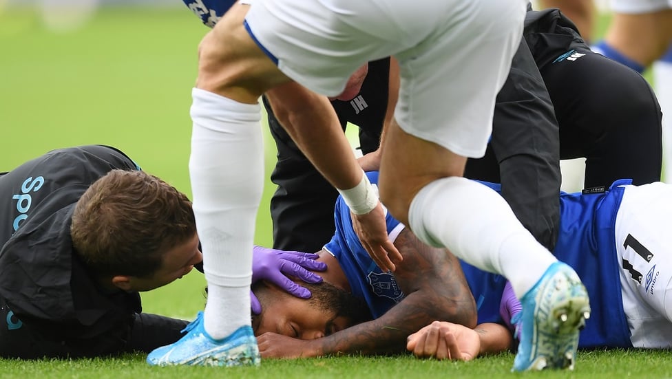 CONCERN : Theo Walcott lies on the ground after being stuck by Sterling's cross