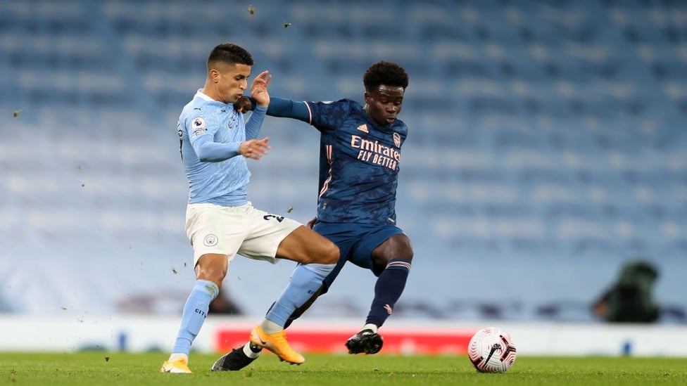 BATTLING JOAO : Cancelo fights Saka for the ball in the first half.